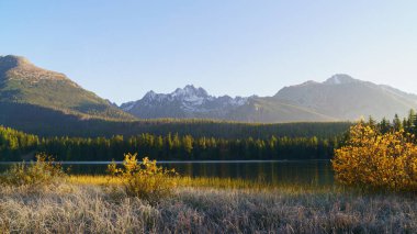 Strbske Pleso 'nun güzel manzaralı panoramik duvar kağıdının arka planında High Tatras dağları milli parkı gün doğumunda. Altın sonbahar manzarası.