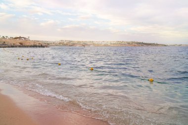 Sakin dalgalar, sahil manzarası ve arka planda kıyı manzarası olan deniz manzarası. Boşluk arkaplanı kopyala.