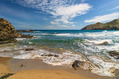 Dalgalar kumlu bir sahile çarpıyor ve güneş ışığı gök mavisi denizden yansıyor. Uzay duvar kağıdını kopyala. Doğanın güzelliği.