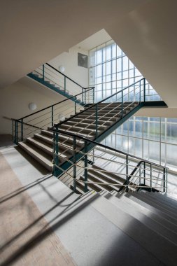 Functionalist building with reinforced concrete construction and creamy white cladding. The interior is dominated by a spacious entrance hall with a distinctive staircase, a functional pater noster and galleries on the upper floors. clipart