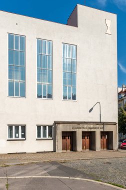 Hus 'un Nusle' deki korosunun inşası 1934 yılında çok amaçlı bir bina olarak tasarlandı. Kısmen basit bir dikdörtgen bina ve sokak köşesinde hafifçe yükseltilmiş prizmatik bir kule var..