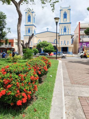 Panama, David kasabası, Cervantes parkının çiçek yatakları ve Kutsal Aile Kilisesi 'nin dış görünüşü. Çekim 21 Mayıs 2022