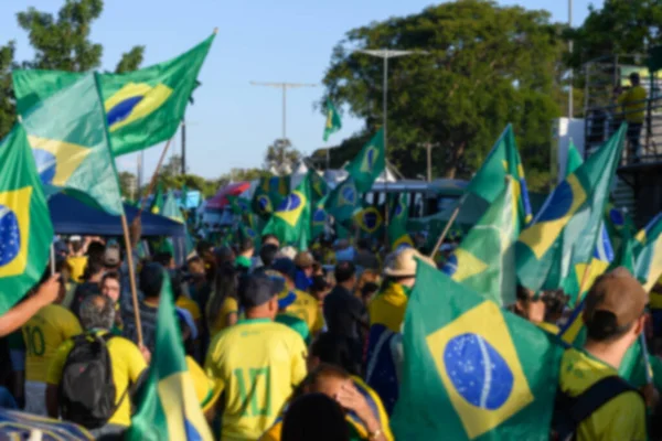 街道上穿着绿色和黄色衣服 举着巴西国旗的巴西人的蓝色背景 足球或政治背景的概念 — 图库照片