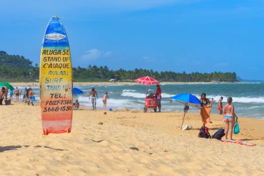 Trancoso, Porto Seguro bölgesi, BA, Brezilya - 06 Ocak 2023: Praia dos Nativos 'un kumlarında sörf ve stand-up dersleri için reklamlarla sıkışıp kalmış sörf tahtası.