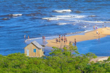 Trancoso, district of Porto Seguro, BA, Brazil - January 06, 2023: the aerial view of the fisherman hut and people on the sand banks of the beach. clipart