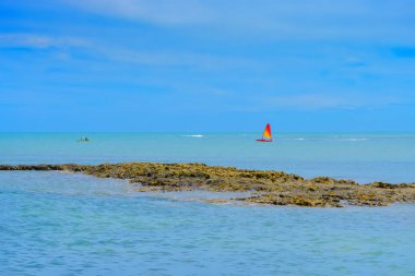 Denizin ortasındaki Espelho Sahili 'nin kayalıklarının güzel manzarası, arka planda bir kaya ve yelkenli tekne. Porto Seguro - Bahia, Brezilya.