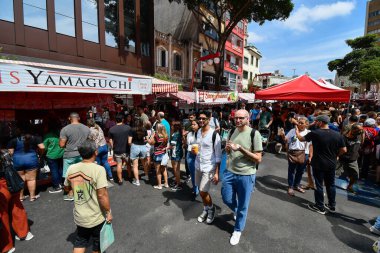 Sao Paulo, SP, Brezilya - 07 Nisan 2024: Liberdade açık hava fuarındaki insanlar yiyecek satan çadırlarda. 