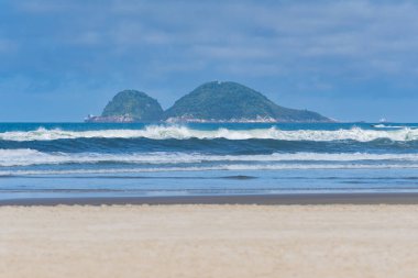 Enseada Plajı 'nda güzel bir günde sabah, kumsal kumsalı, deniz manzarası ve arka planda Farol da Moela adası. Guaruja - SP, Brezilya.