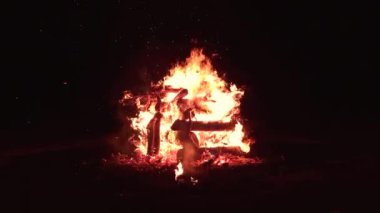 Ateşe körükle giden, alevlerle yanan odunlardan yapılmış şenlik ateşi. Karanlıkta izole edilmiş şenlik ateşi. Etrafta kimse yok..