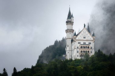 Fussen 'deki Neuschwanstein Şatosu, XIX yüzyılının şaşırtıcı neo gotik sarayı ve Almanya' nın en ünlü Bavyerası. Yağmurlu ve sisli bir günde uzaktan bak