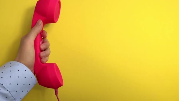 黄色の背景にピンクの電話をかける女性 スローモーションでの通信 — ストック動画