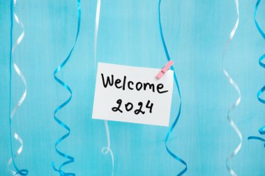 Hoş geldiniz 2024 - ipte mandal yazılı kart, mavi ve beyaz süslemeli yeni yıl konsepti