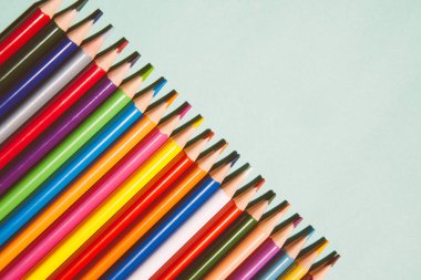 Açık yeşil zemin üzerinde farklı renk kalemler kopya alanı, sanat kartı