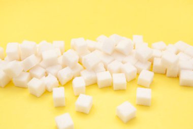 Sarı zemin üzerinde beyaz şeker küpleri, tatlı yemek malzemeleri.