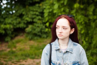 Çilli, üzgün ve üzgün genç bir kadın dışarıda, parkta üzgün görünüyor. 