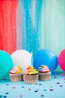 Renkli kekler ya da bir mum ve hava balonlu kekler mavi, dikey mutlu yıllar kartı ve fotokopi alanı