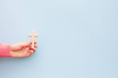 Açık mavi zemin üzerinde ahşap haç ve kopya alanı, Hıristiyan inancı ve inanç konsepti ile el.