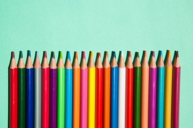 Yeşil arka planda farklı renk kalemleri satırı, okula geri dön 