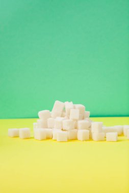Yeşil ve sarı dikey arkaplanda beyaz şeker küpleri, tatlı besin maddeleri