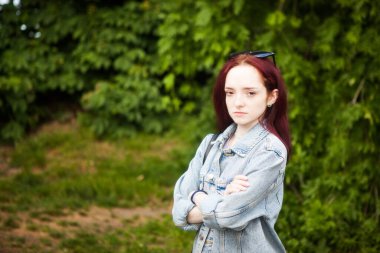 Çilli, ciddi bir genç kadın, dışarıda kameraya bakıyor.