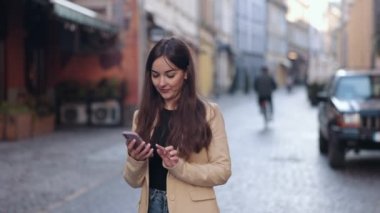 Gülümseyen iş kadını, konuşan cep telefonu, konuşan kadın. Dost canlısı bir bayanın yürüdüğünü gösteren bir portre. Şehirde yürürken telefonda konuşan çekici bir sırt çantalı. Güzel bir kadın tek başına dolaşıyor.