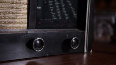 Eski moda bir radyo oynatıcısı 1950 'lerden kalma klasik bir iç mimari ile masa başında duruyor. Fm kanalı müzik çalıyor ve el radyoyu açıyor..