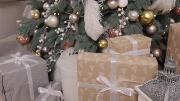 圣诞节 圣诞礼品盒 冷杉树圣诞背景 有彩带和装饰品 美丽的礼品盒在枞树附近的地板上 庆祝活动 礼品盒上系有彩带 — 图库视频影像