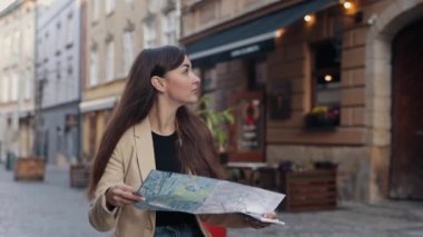 Şehir haritası, turistik yerler, seyahat aksesuarları. Tatil sırasında yabancı bir şehirde bir atlas üzerinde otelin yolunu arayan turistler, modaya uygun gezen mutlu kadın gezgin, yönleri arıyor