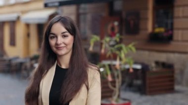 Kameraya, modellere, genç kadınlara bakıyorum. Gündelik giysiler içinde, açık havada poz veren genç bir kadının yakın plan portresi beyaz bir kadın, gülümseyen ve gülen güzel bir kız..