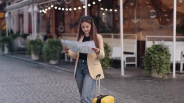 Kadın yolcu, bavul kullanımı, otel varış yerleri. Haritaya bakan genç bir kadın, güzel, pozitif bir bayan turist trendli gezgin yurtdışına seyahat ederken haritada yön arıyor.