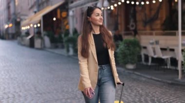 Seyahat eden bir kadın, valiz, tatil gezisi, Avrupa 'da sokakta yürüyen bavullu bir turist, turist konsepti, bavulla yürüyen genç bir kız, Avrupa' da turizm, kadın.