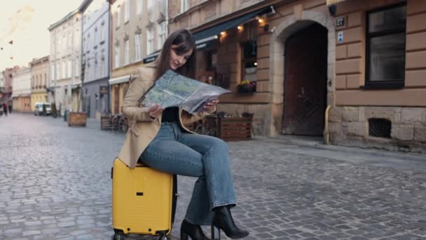 出国旅游 女性游客 搜索方向 一个快乐的女人在夏天出国旅行时在地图上寻找方向 一个快乐的游客在地图上寻找方向 — 图库视频影像