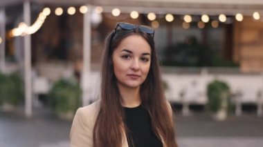 Gülümse, mutlu ol, genç bayan. Dışarıda poz veren genç bir kadın, mutlu ve gülümseyen bir yüz, beyaz bir kadın portresi, genç bir kadının yakın plan portresi.