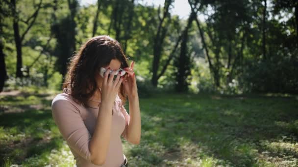 仮想現実とタッチスクリーンで屋外公園の芝生の上に立つ 自然と完全にブレンド美しい女性 — ストック動画