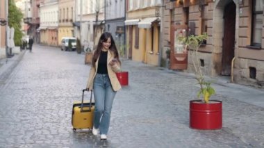 Gezgin kadın, bavul, eve dönüş, tatiller. Avrupa 'da sokakta bavulla gezen kadın turist, Avrupa' da turizm, sokakta bavulları taşıyan genç kız gezgin.