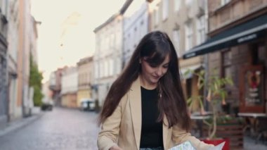 Yurtdışına seyahat, turist aramak, tatil planlamak. Neşeli bir kadın, yaz aylarında yabancı bir şehirde tatildeyken haritada yol tarifi arıyor.