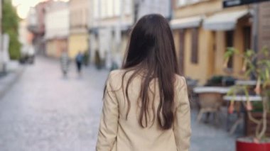 Açık havada gezen, şık bir kadın, arka tarafı takip ediyor. Enfes, şık, genç, kaygısız, neşeli esmer kadın şehirde dönüyor. Dönüyor, eğleniyor, sokakta, arka manzarada kameraya bakıyor.