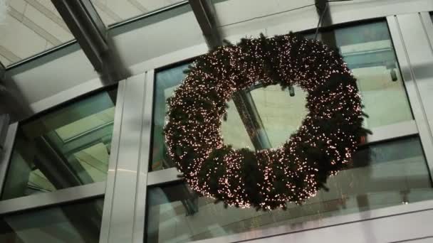リースクリスマス オフィスドア 休日の季節 スプルースで覆われたクリスマスリースは休日の季節の間にフロントオフィスドアにかかっています — ストック動画