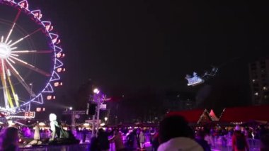 Berlin, Almanya - 26 Aralık 2021 Noel, Noel Baba, Kış Şehri. Noel Baba 'nın şehir manzarasına karşı hediye kutusuyla kızağa bindiği, ren geyiklerine bindiği ve Noel Perisi' nin üzerinde uçtuğu sahne.