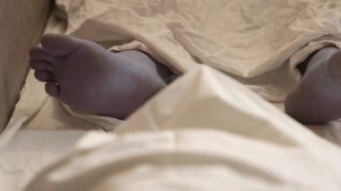 Human corpse covered with a sheet in morgue. Homo dead comprise with sheet. Human corpse covered with bedsheet, in morgue. Death from covid-19 and protection from virus global.