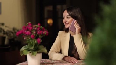 Kadın konuşması, serbest çalışan kız, cep telefonu. Avrupa 'daki kafede, güzel gülüşlü genç bir bayan boş zamanlarında cep telefonuyla tek başına otururken bir telefon görüşmesi yapıyor..