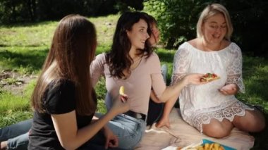 Kadın pikniği, kadın arkadaşlar, grup, doğada meyveli, sandviçli, jambonlu sandviçli ve sağlıklı beslenen bir grup arkadaş.