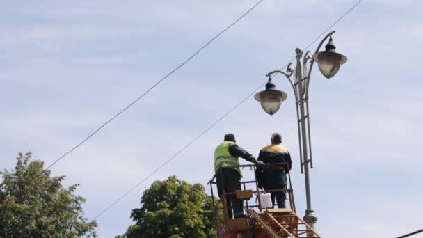 电气技术 安装过程中 工人们致力于在高处修理街灯 更换灯具 用吊桶固定灯柱灯 穿戴个人防护设备 — 图库视频影像