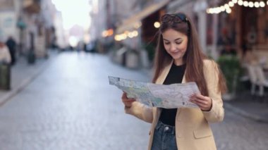 Harita kontrolü, kadın turist, seyahat yaşam tarzı. Güzel, pozitif, modaya uygun gezgin bayan turist, yazın valiziyle yurtdışına seyahat ederken haritada yön bulma arayışında..