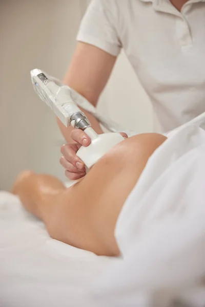 beauty clinic, roller massage, lymphatic drainage. Young woman from beauty salon performs beauty services, body shaping, masseurs perform vacuum roller massages for clients, figure correcting