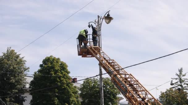 労働者の修理ダイオードライト街灯 街路灯の修理作業 架線灯の高さを補修する作業員 新しい誘導灯を設置する作業員 照明を固定する作業員 — ストック動画
