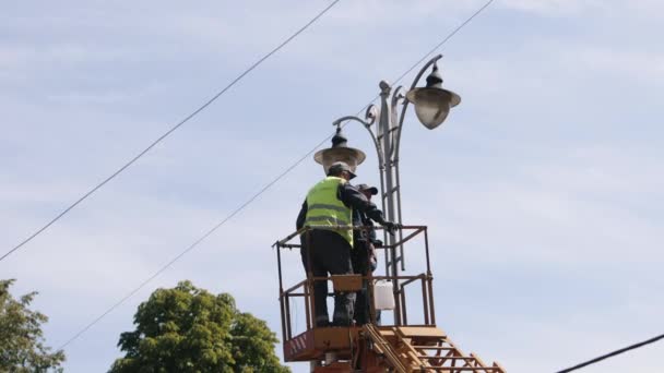 固定灯 街头电线杆需要修理 工人们正在爬梯子维修街灯 在街上换灯泡 — 图库视频影像
