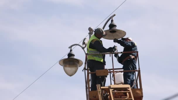 前导灯 空中技师 街头小灯维修车间的员工致力于在高处修理街头小灯 更换铅灯 男人爬上电梯桶 — 图库视频影像
