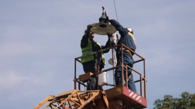 during installation, worker repair, metal pole. Worker is fixing street light pole lamp at height, replacing led lights. Men fixing lamp pole lamp, fixing street light
