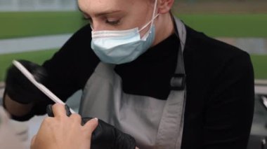 clients nails, manicure master, manicurist filing. Manicurist files clients nails at table, spa treatment, young womans hands are being filed with nail file by manicurist in nail salon, give shape